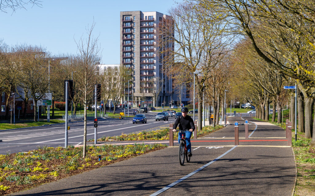 Cyclist on the new sustainable transport corridor with Burnt Mill in the background